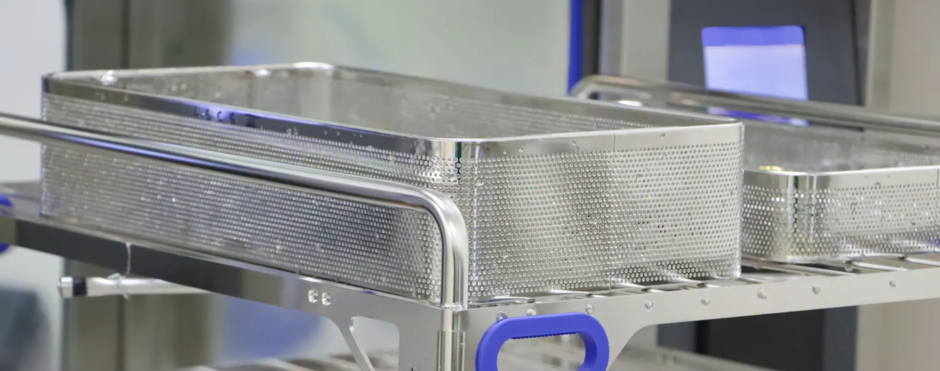 Stainless steel sterilization trays on a rolling cart in a medical equipment processing area.