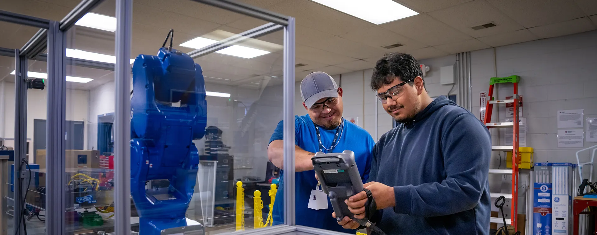 Students review wiring connections on an industrial control panel in an industrial maintenance lab.