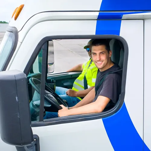 Student sits in the driver&rsquo;s seat of a CDL training truck while an instructor rides in the passenger seat.