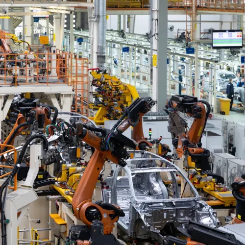 Industrial robots welding and assembling vehicle bodies on an automated manufacturing line.