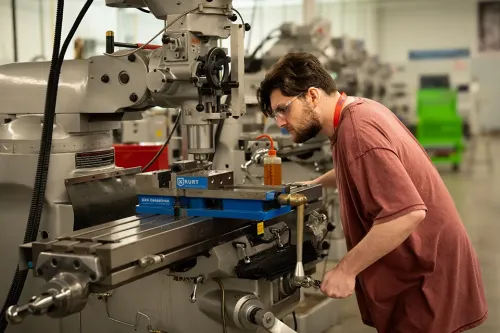 Student adjusts a milling machine while wearing safety glasses in a machining workshop.